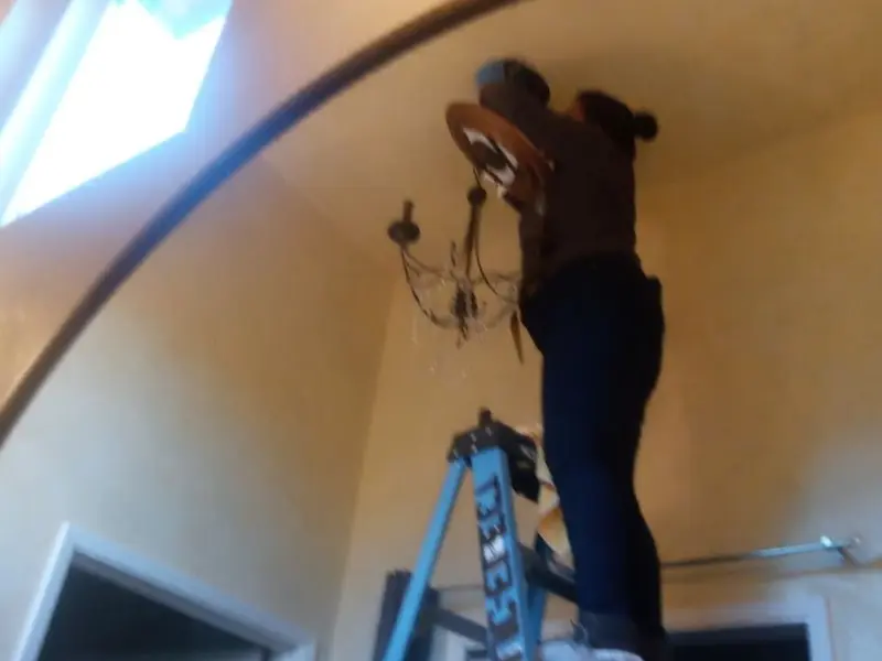 Electrician installing a chandelier in a Davison residence